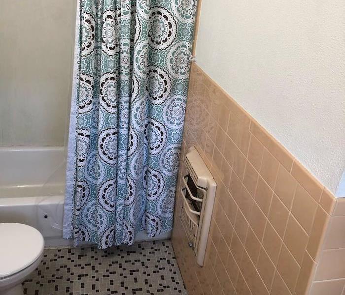 Bathroom with the shower curtain pulled back showing the tub