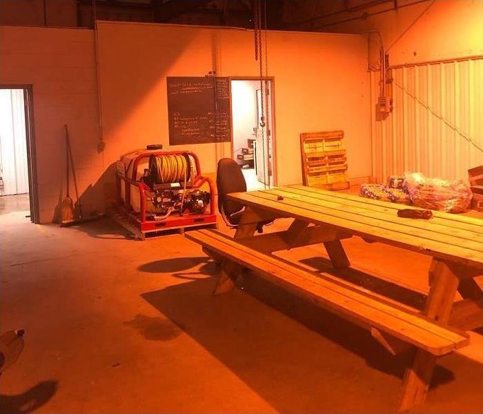picnic table inside warehouse; doors to offices shown