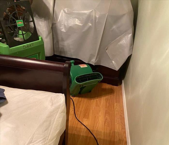 Bed with SERVPRO drying equipment on wood floor
