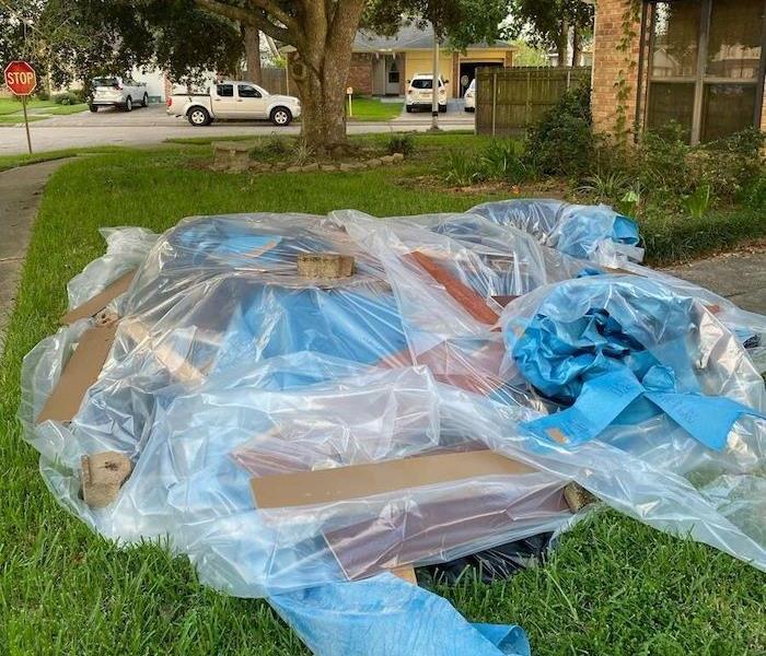 Articles in a front yard with plastic covering