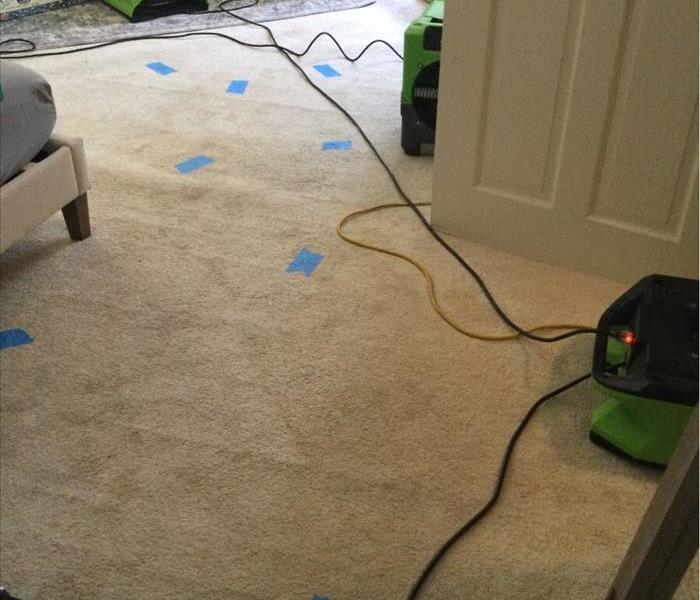 Air movers and dehumidifier operating on carpet marked with blue tape