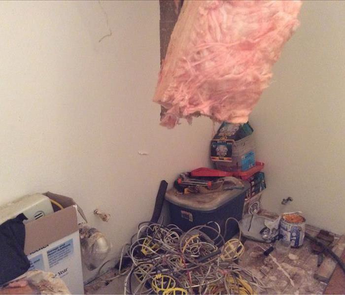 Room with scattered contents, removed baseboards, ceiling with insulation hanging down