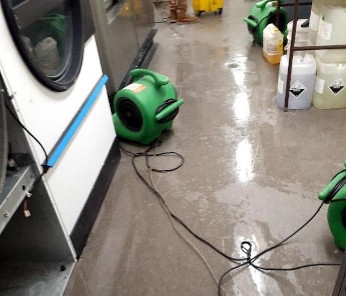 Washing machine on wet concrete floor with SERVPRO drying equipment