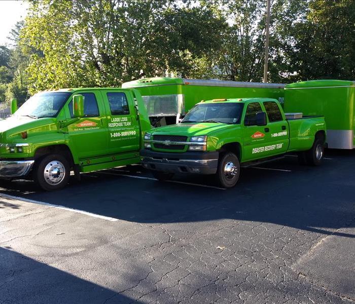 Green SERVPRO trucks with trailers in a parking lot