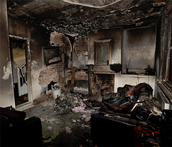 a fire damaged room with debris everywhere and soot covering everything