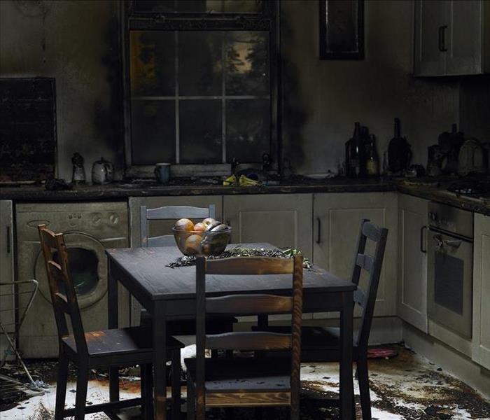 a fire damaged kitchen with soot covering the furniture and debris on the floor